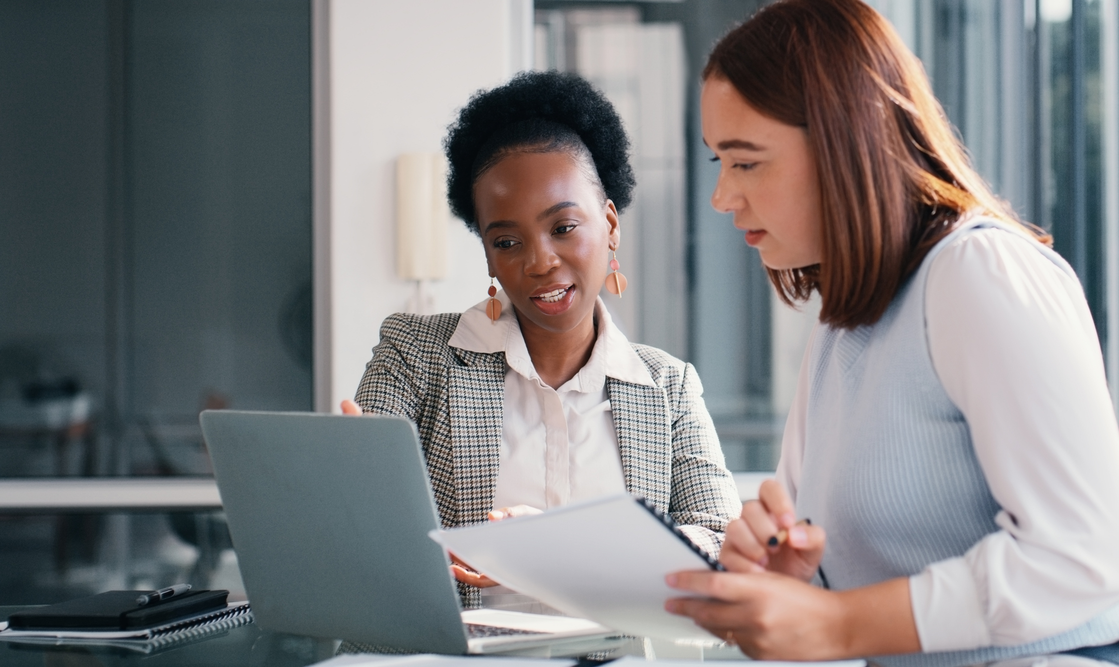 Paper, laptop and people in office for meeting, financial planning and business discussion. Women, document or tech at table for admin, budget review or audit information for company growth and taxes