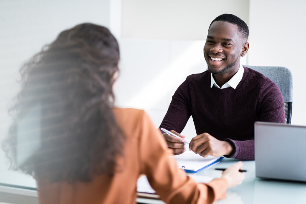 A man smiling while discussing a performance review with colleague.